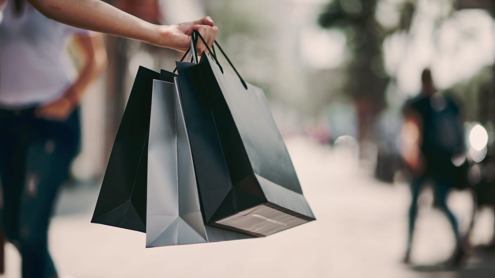 Close up of woman`s hand holding shopping bags while walking on the street.