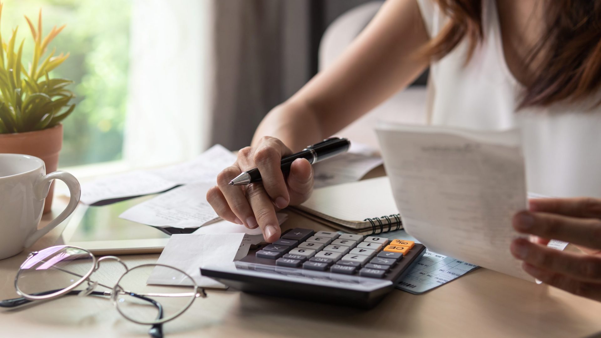 Stressed young woman checking bills, taxes, bank account balance and calculating expenses in the living room at home