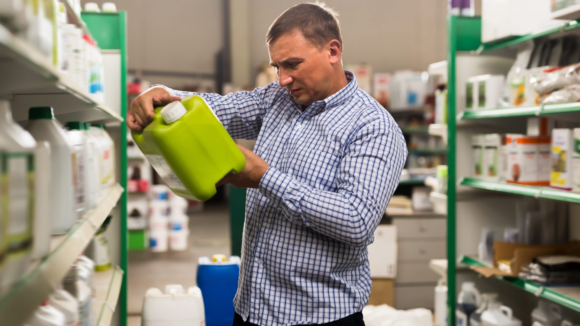 Man buying liquid fertilizer for gardening in hypermarket